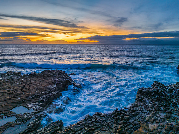 Sunrise over the sea and rock platform with high cloud