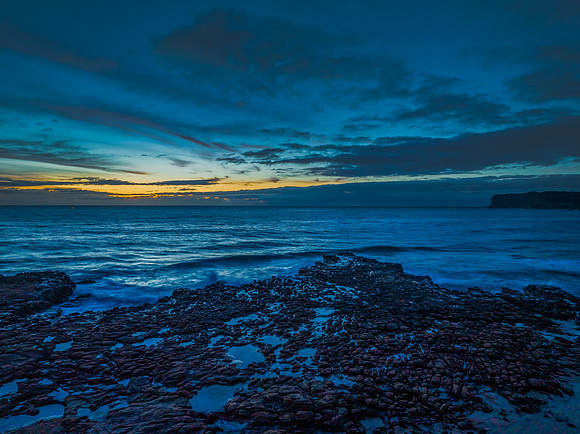 Sunrise over the sea and rock platform with high cloud