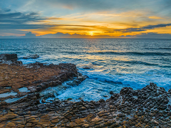 Sunrise over the sea and rock platform with high cloud