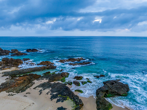 Rain clouds, rocks and sunrise at the seaside