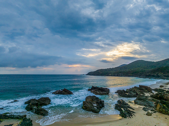 Rain clouds, rocks and sunrise at the seaside
