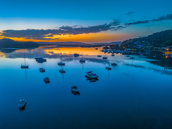 Aerial sunrise waterscape with boats, reflections and low cloud