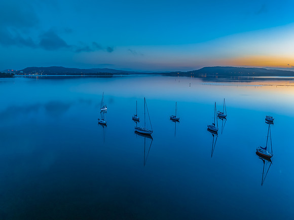Aerial sunrise waterscape with boats, reflections and low cloud