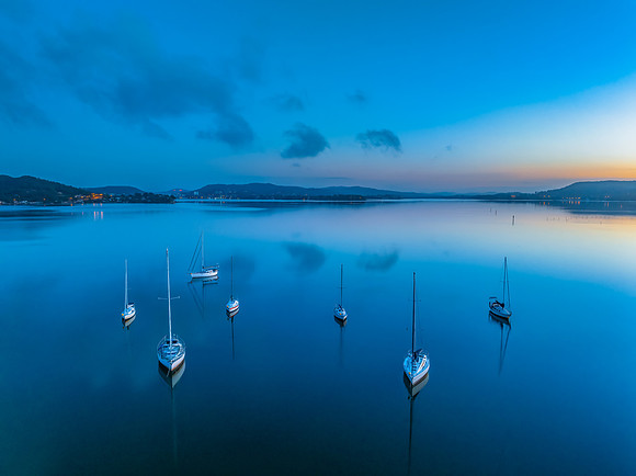 Aerial sunrise waterscape with boats, reflections and low cloud