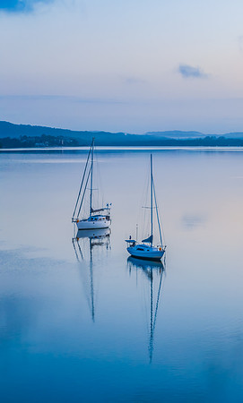 Aerial sunrise waterscape with boats, reflections and low cloud