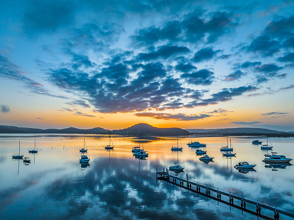 Aerial sunrise waterscape with boats, reflections and low cloud