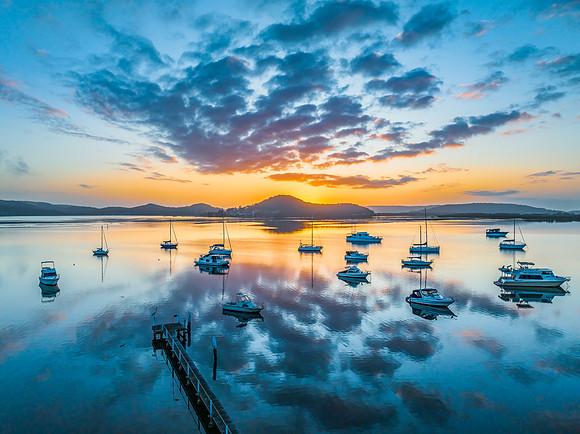Aerial sunrise waterscape with boats, reflections and low cloud