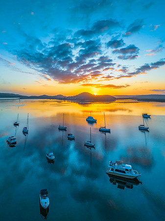 Aerial sunrise waterscape with boats, reflections and low cloud