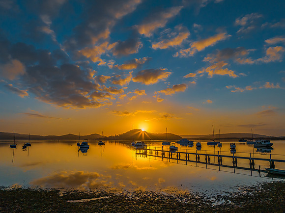 Aerial sunrise waterscape with boats, reflections and low cloud
