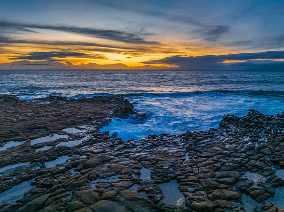 Sunrise over the sea and rock platform with high cloud