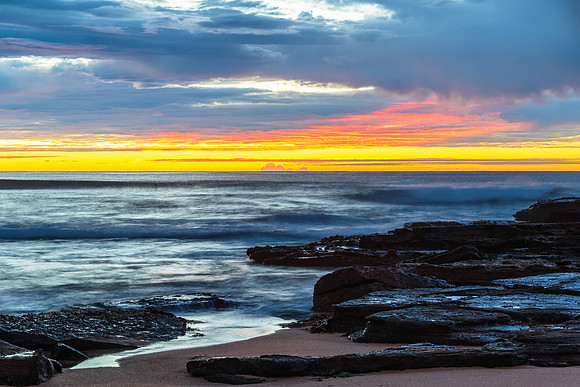 Winter sunrise by the sea shore with rain clouds