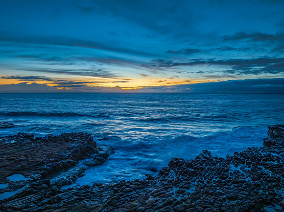 Sunrise over the sea and rock platform with high cloud