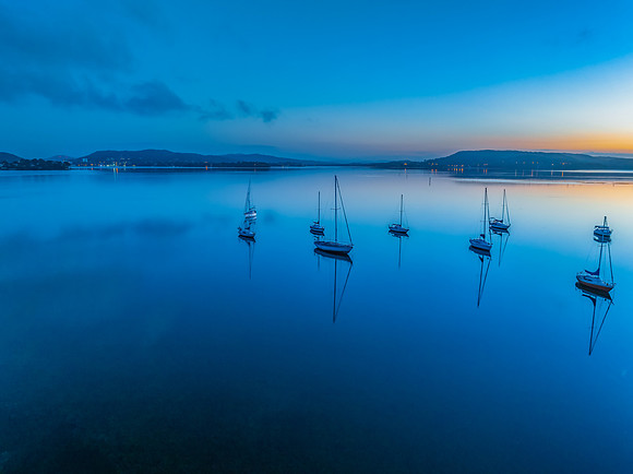 Aerial sunrise waterscape with boats, reflections and low cloud