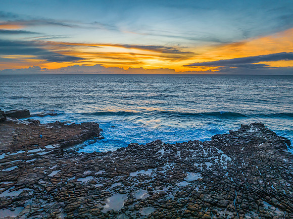 Sunrise over the sea and rock platform with high cloud
