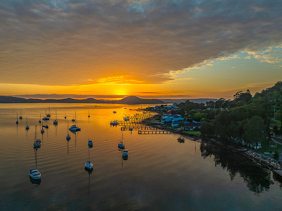 Aerial sunrise over the water with boats and clouds