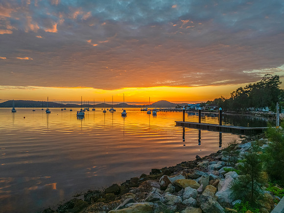 Aerial sunrise over the water with boats and clouds