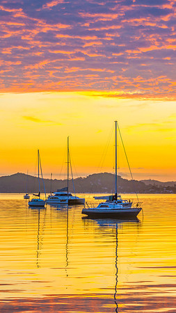 Aerial sunrise over the water with boats and clouds