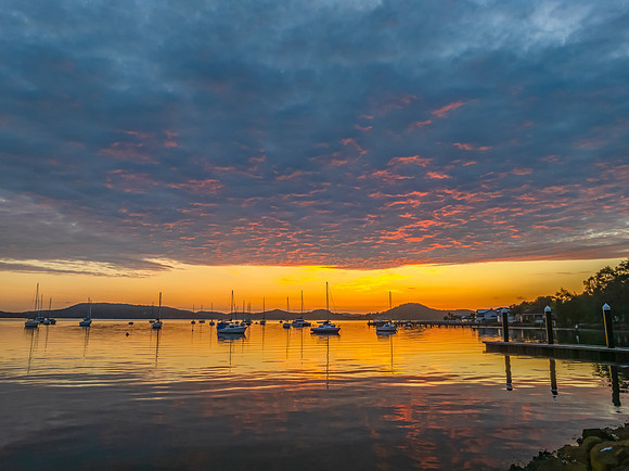 Aerial sunrise over the water with boats and clouds