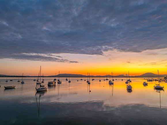 Aerial sunrise over the water with boats and clouds