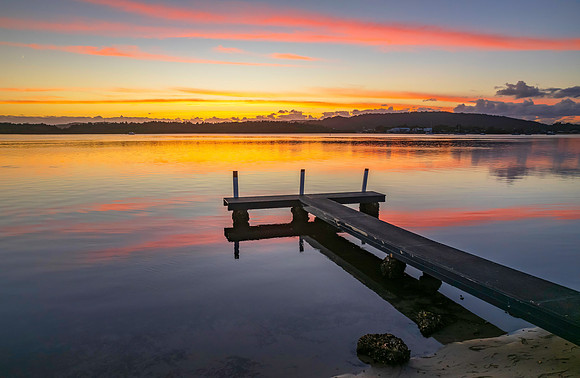 Sunrise over the bay with clouds and wharf