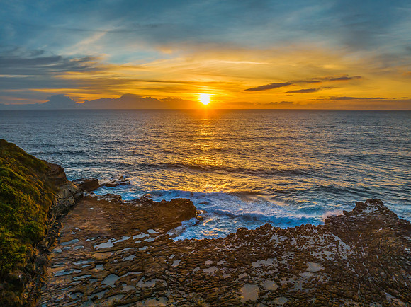 Sunrise over the sea and rock platform with high cloud