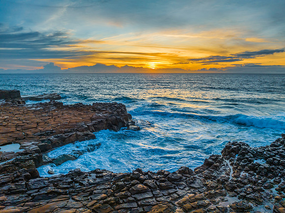 Sunrise over the sea and rock platform with high cloud