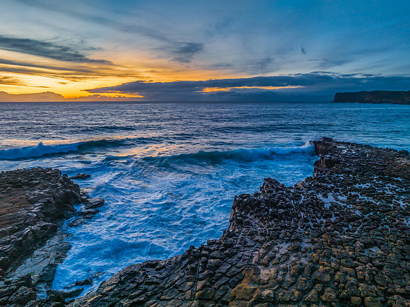 Sunrise over the sea and rock platform with high cloud