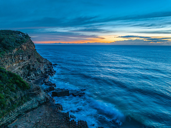 Sunrise over the sea and rock platform with high cloud