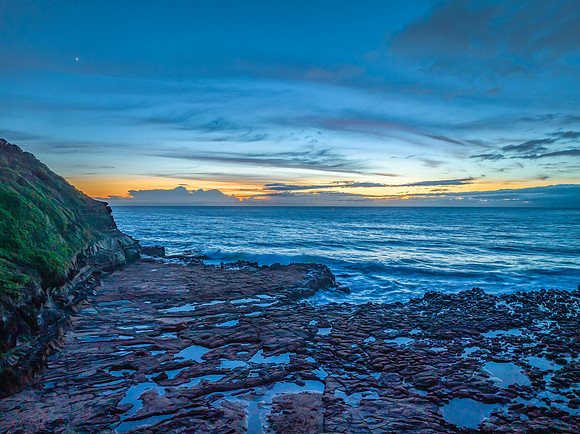 Sunrise over the sea and rock platform with high cloud