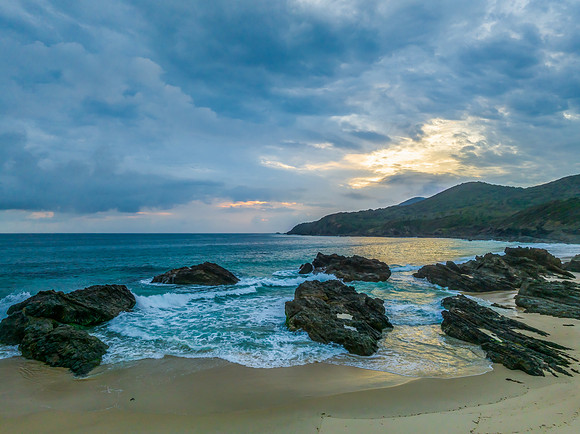 Rain clouds, rocks and sunrise at the seaside
