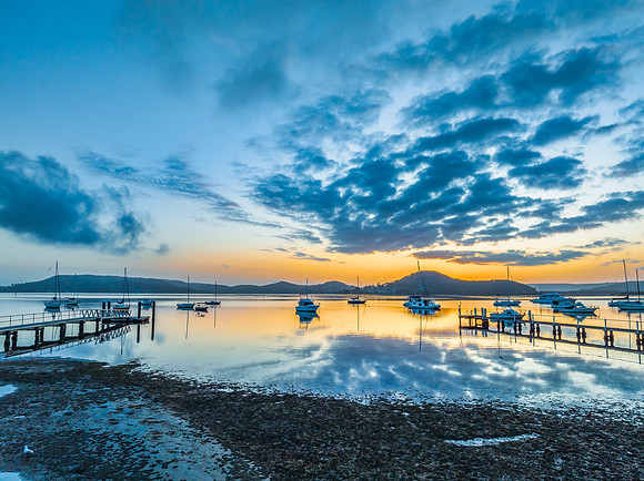 Aerial sunrise waterscape with boats, reflections and low cloud