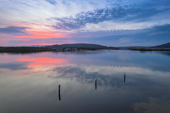 Soft and peaceful sunrise aerial waterscape with clouds and refl