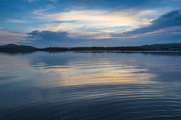 Soft and peaceful sunrise aerial waterscape with clouds and refl