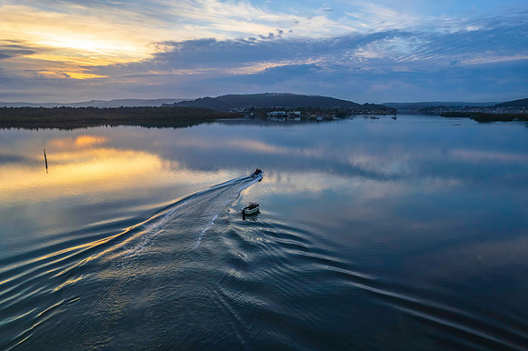 Soft and peaceful sunrise aerial waterscape with clouds and refl