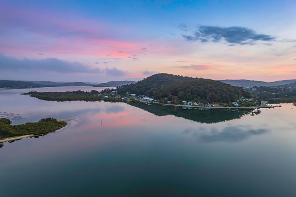 Soft and peaceful sunrise aerial waterscape with clouds and refl