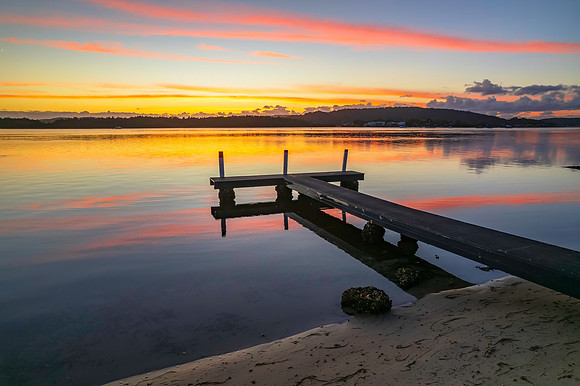 Sunrise over the bay with clouds and wharf