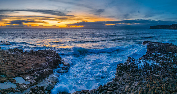 Sunrise over the sea and rock platform with high cloud