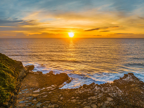 Sunrise over the sea and rock platform with high cloud