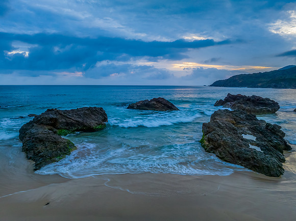 Rain clouds, rocks and sunrise at the seaside
