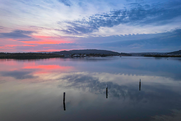 Soft and peaceful sunrise aerial waterscape with clouds and refl