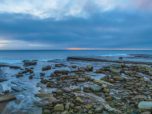 Sunrise seascape and rocky Inlet with thick fog cloud over the o