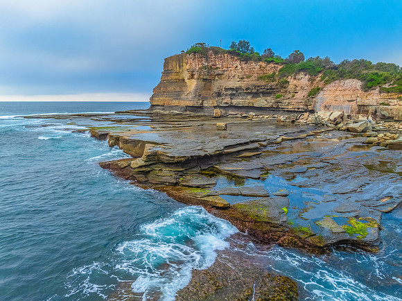 Sunrise seascape and rocky Inlet with thick fog cloud over the o