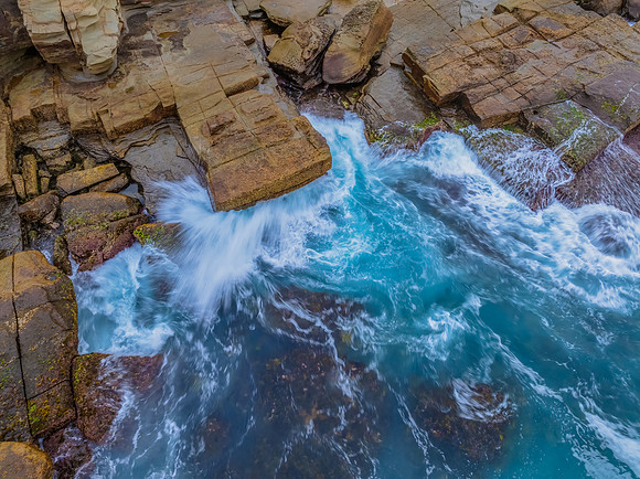 Sunrise and the blue sea washing over the rock platform