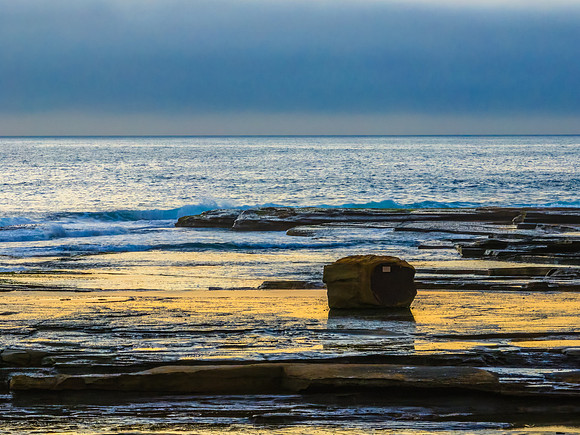 Sunrise seascape and rocky Inlet with thick fog cloud over the o