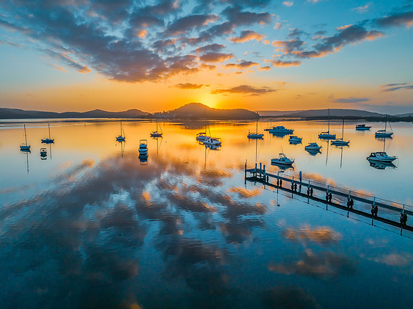 Aerial sunrise waterscape with boats, reflections and low cloud