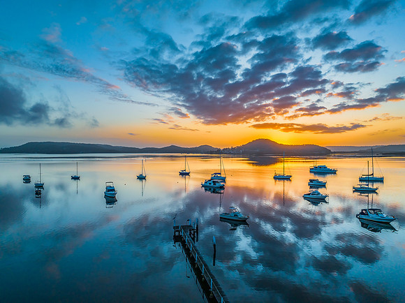 Aerial sunrise waterscape with boats, reflections and low cloud
