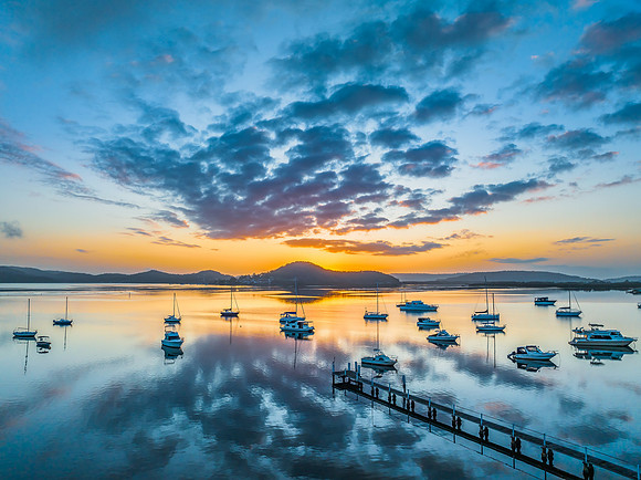 Aerial sunrise waterscape with boats, reflections and low cloud