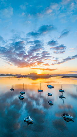 Aerial sunrise waterscape with boats, reflections and low cloud