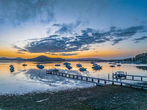 Aerial sunrise waterscape with boats, reflections and low cloud