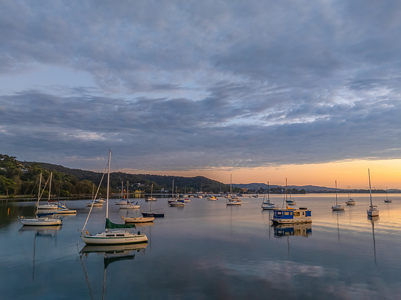 Aerial sunrise over the water with boats and clouds